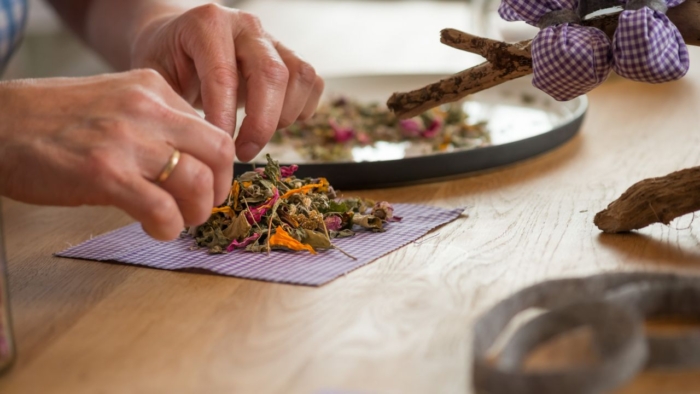 Jemand belegt kleine Stoffstücke mit Räuchermischungen.