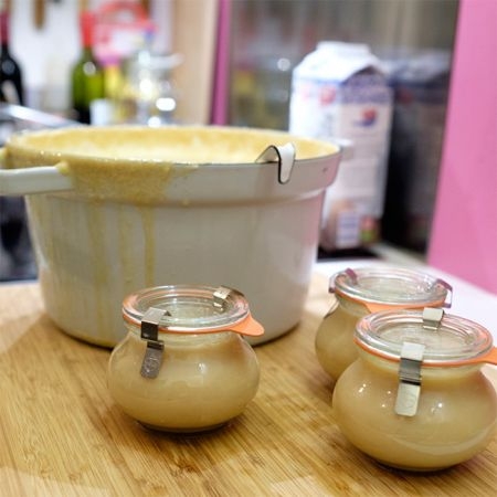 Drei Einmachgläser mit Confiture de Lait vor einem Kochtopf und einer Ja! Natürlich Bio-Milch.