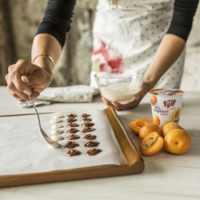 Jemand tröpfelt Ja! Natürlich Bio-Joghurt auf ein Backpapier.