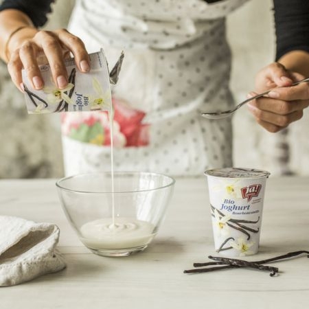 Jemand leert einen Ja! Natürlich Bio-Vanille-Joghurt in eine Schale.