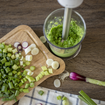 Jemand mixt Bio-Jungzwiebel mit einem Stabmixer.