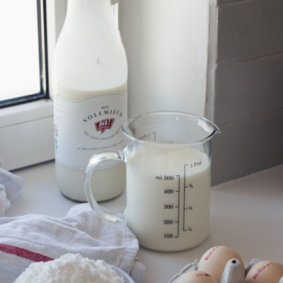 Ja! Natürlich Bio-Milch im Glas mit einem Messbecher mit Milch.