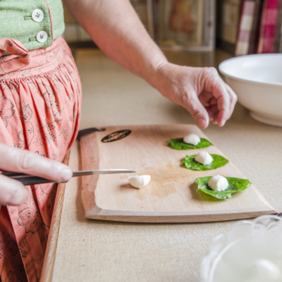 Jemand legt Bio-Mini-Mozzarella auf Spinatblätter.