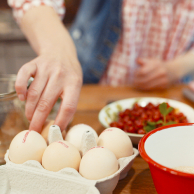 Jemand nimmt ein Bio-Ei aus einem Karton.