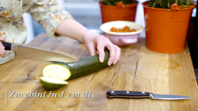 Jemand schneidet Bio-Zucchini.