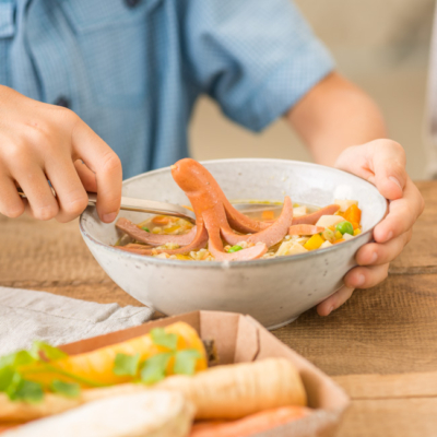 Bunte Nudel-Suppe mit Würstel-Oktopus in einer Schale.