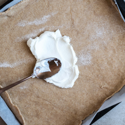 Bio-Ziegenkäse wird auf einen Teig gestrichen.