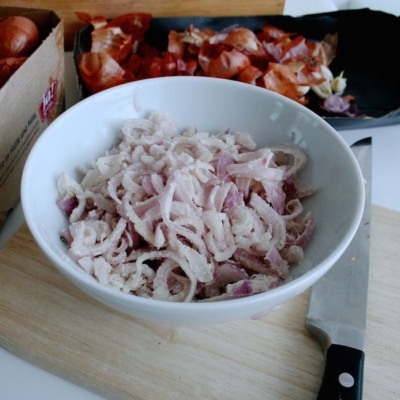 Eine Schüssel mit feingeschnittenen Bio-Schalottenstreifen, in Weizenmehl gewälzt.