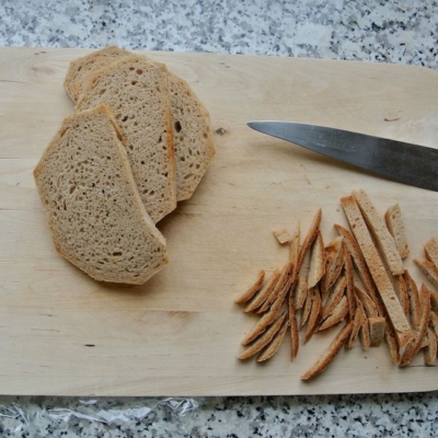 Bio-Brotscheiben auf einem Schneidebrett, daneben der abgeschnittene Rand.