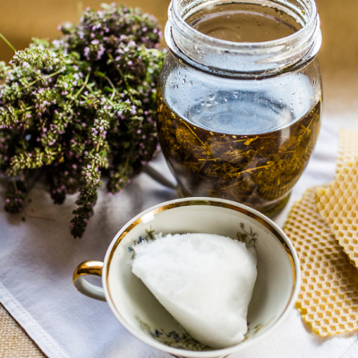 Bio-Thymian, ein Glas mit Thymianöl und eine Tasse mit Sheabutter.