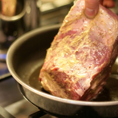 Jemand legt Bio-Fleisch in eine Pfanne.