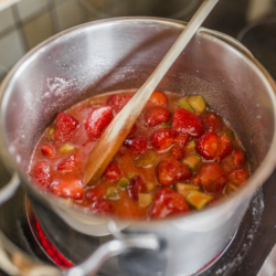 Jemand kocht Bio-Erdbeer- und Rhabarbermarmelade ein.