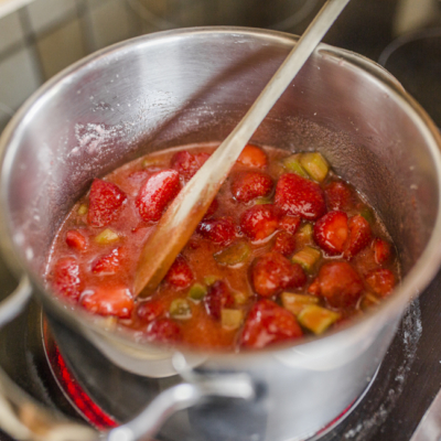 Jemand kocht Bio-Erdbeer- und Rhabarbermarmelade ein.