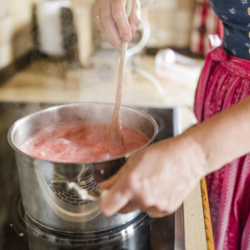 Jemand kocht Marmelade in einem Topf und rührt um.