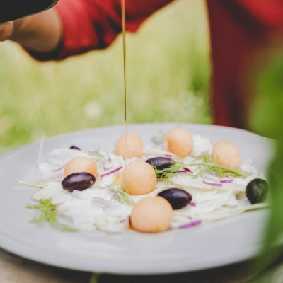 Jemand garniert einen Fenchelsalat mit Bio-Öl.
