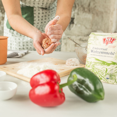 Jemand formt Kugeln aus einem Teig mit Ja! Natürlich Bio-Weizenmehl.