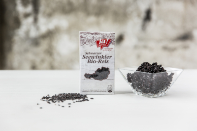 Eine Packung schwarzer Bio-Seewinkler Reis mit einer Schüssel daneben.