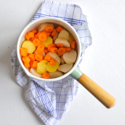 Geschnittene Bio-Karotten, Erdäpfel und Topinambur in einem Kochtopf.