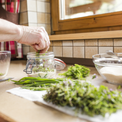 Jemand füllt Bio-Kräuter in ein Glas.
