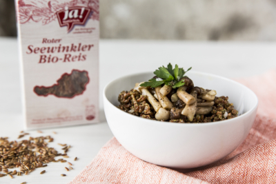 Eine Schüssel mit einem Reisgericht vor einer Packung Ja! Natürlich Seewinkler Bio-Reis.