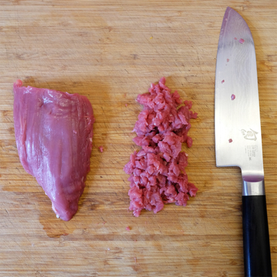 Ein Stück Bio-Fleisch, daneben gehacktes Fleisch und ein Messer.