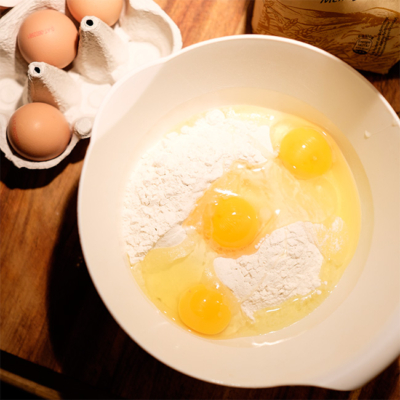Drei Bio-Eier und Mehl in einer Schüssel.