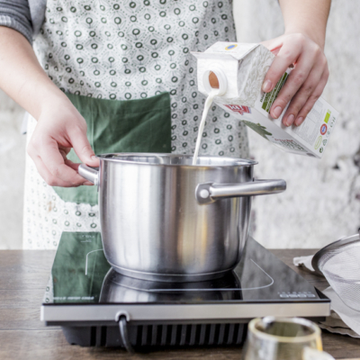 Jemand leert Ja! Natürlich Bio-Heublumenmilch in einen Topf.