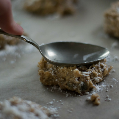 Ein Keksteig wird mit einem Löffel flach gedrückt.