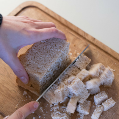 Jemand schneidet Bio-Toast in Würfel.