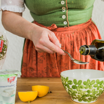 Jemand gibt Bio-Olivenöl in eine Schüssel.