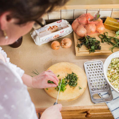 Jemand schneidet Bio-Gewürze auf einem Schneidebrett.