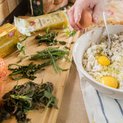 Jemand schlägt ein Bio-Ei in eine Schüssel mit zwei Eiern und Knödelmasse.