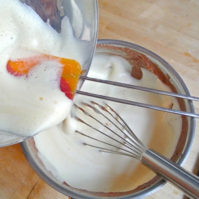 Jemand gießt Bio-Eischnee in eine Schokomasse.