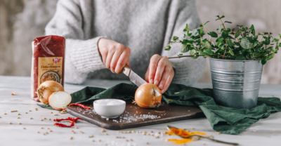 Jemand halbiert eine Zwiebel, daneben eine Packung Ja! Natürlich Bio-Linsenteller.