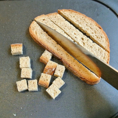 Jemand schneidet Bio-Brot in Würfel.