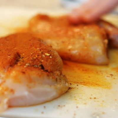 Gewürzte Bio-Hühnerbrust auf einem Schneidebrett.