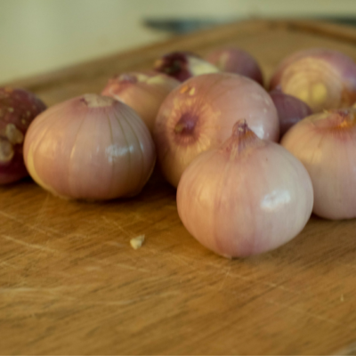 Geschälte Bio-Zwiebeln auf einem Schneidebrett.