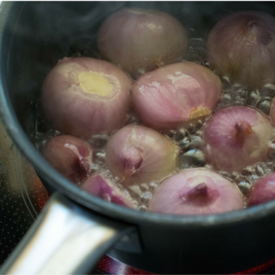 Geschälte Bio-Zwiebeln in einem Kochtopf.