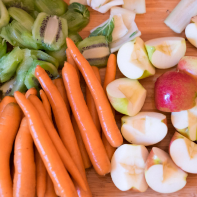 Bio-Karotten und Äpfel auf einem Schneidebrett.