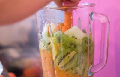 Jemand gibt Bio-Obst in einen Mixer.