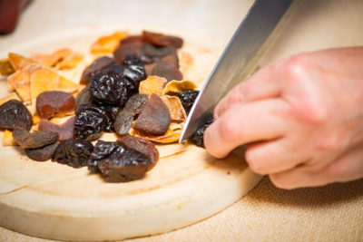 Jemand schneidet getrocknetes Bio-Dörrobst auf einem Brett.