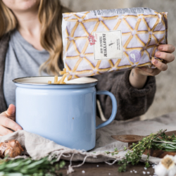 Jemand schüttet Ja! Natürlich Bio-Makkaroni in einen Topf.