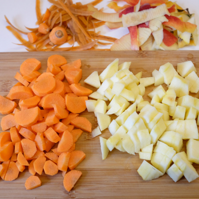 Geschnittene Bio-Karotten und Äpfel auf einem Brett.