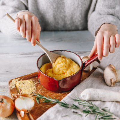 Jemand rührt Bio-Polenta in einem Topf um.