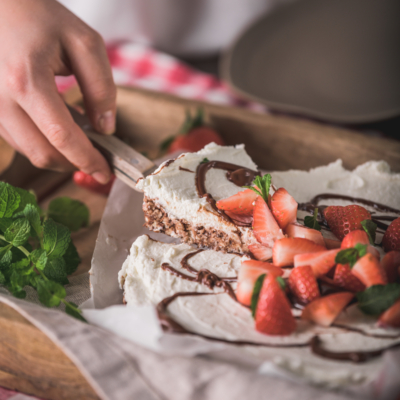 Jemand nimmt ein Stück Torte mit Bio-Erdbeeren.