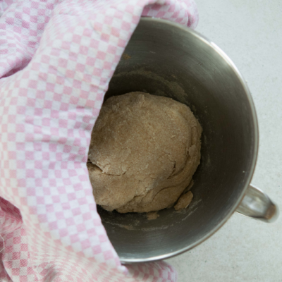 Jemand bedeckt einen Teig mit einem Geschirrtuch.