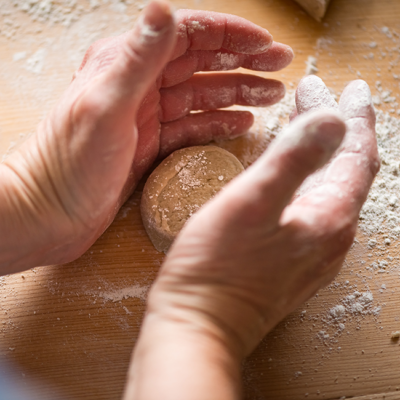 Jemand formt Teig am Tisch.