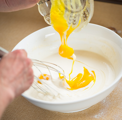 Jemand mixt Bio-Eigelb unter.