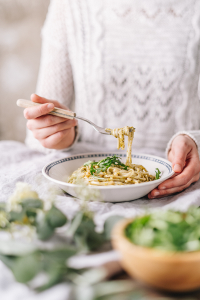 Jemand hält eine Gabel mit einem Bio-Spaghetti-Gericht.