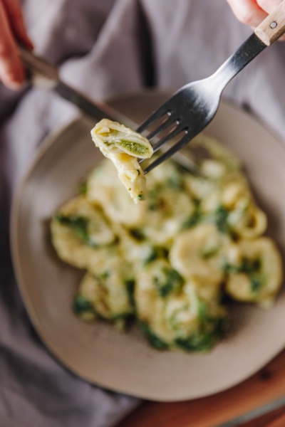 Ein Bissen eines Tortelloni-Gerichts wird auf einer Gabel präsentiert.
